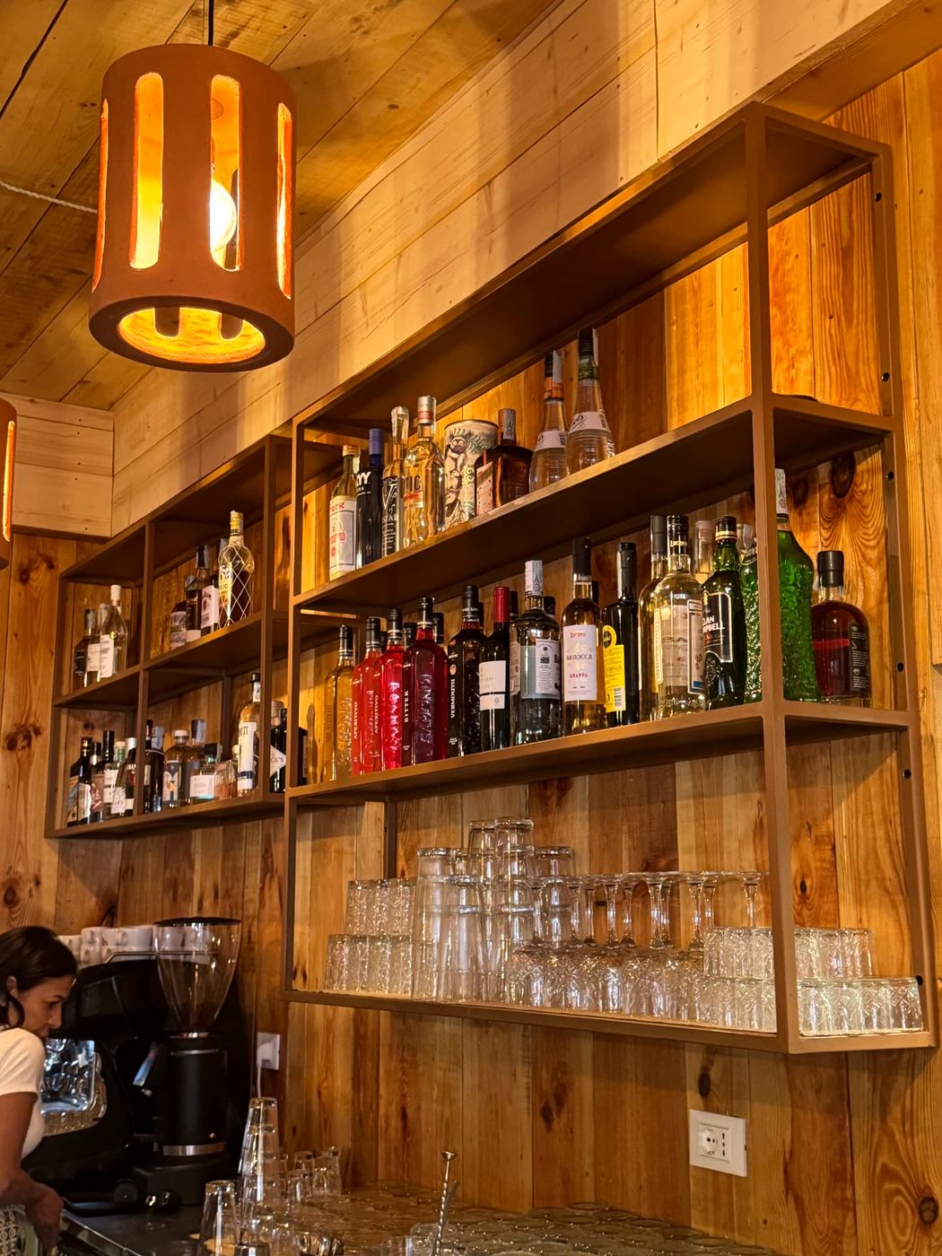 Il bancone del bar con le bottiglie sugli scaffali in legno